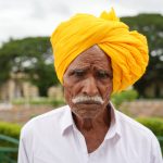 Hombre con turbante amarillo contemplando una plantación de té entre montañas